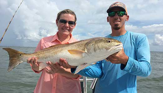 Couple holding redfish caught on Galveston fishing trip