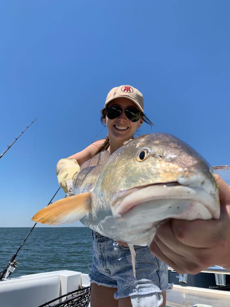 Young lady holds redfish close to camera while on a Spring time Galveston fishing trip