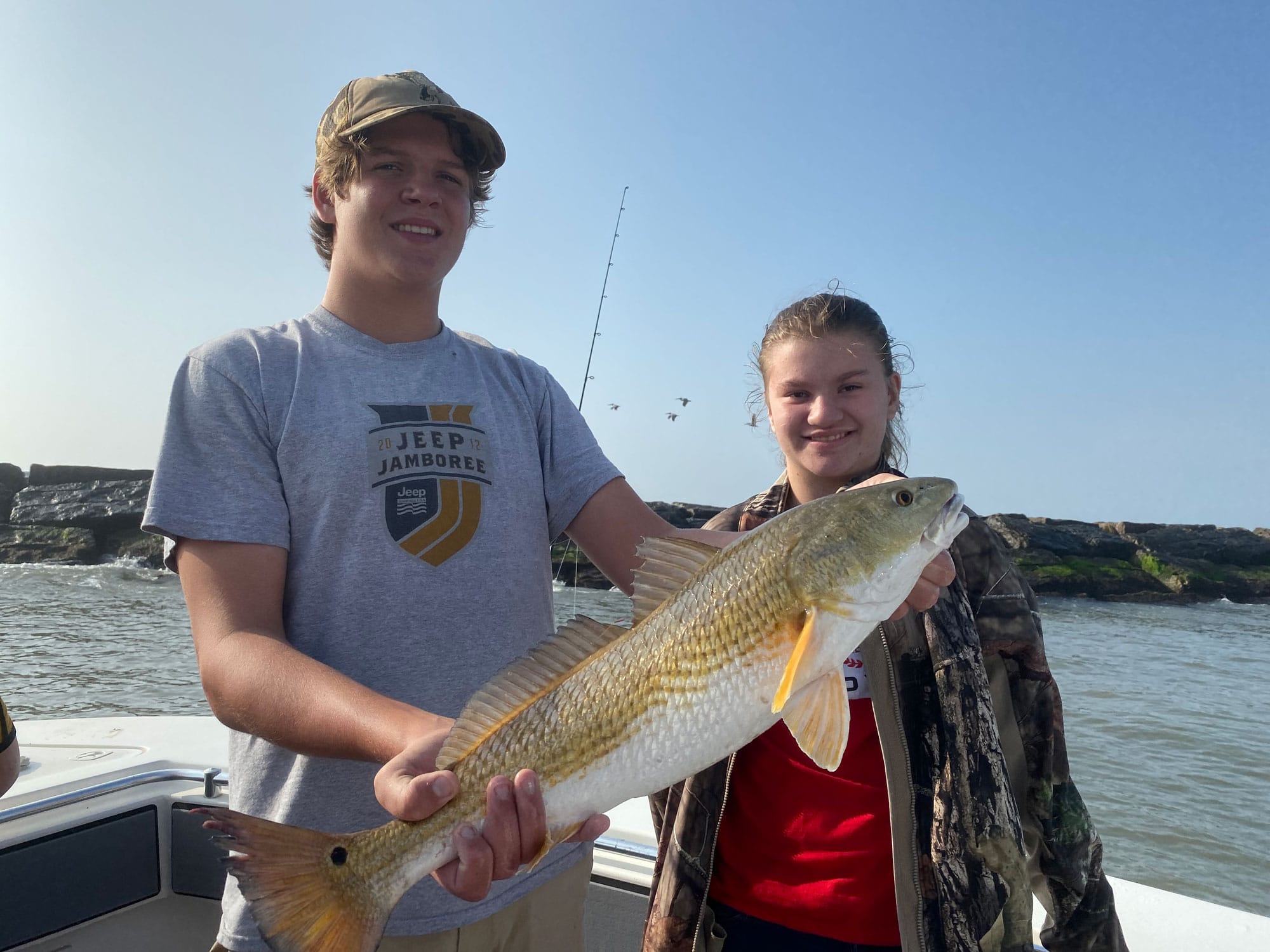 Two teenagers holding redfish caught in Galveston in February