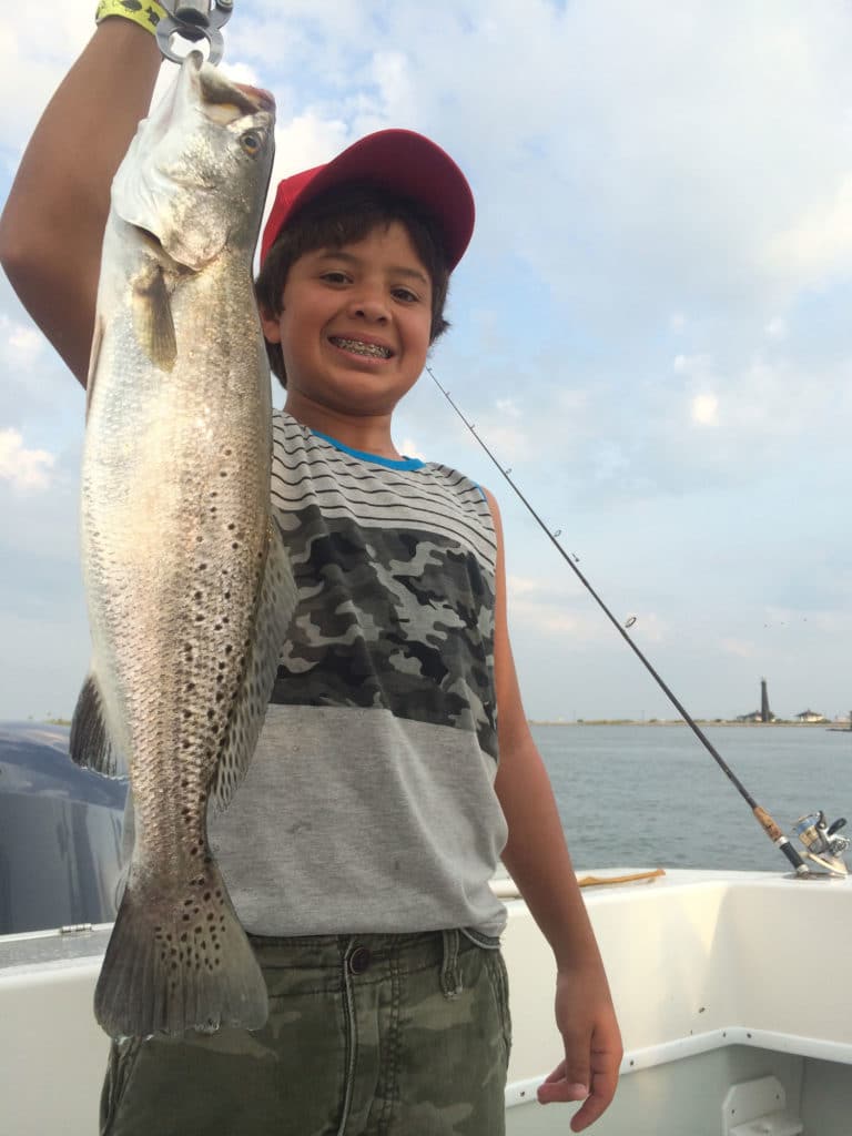 Young boy with braces holding speckled trout