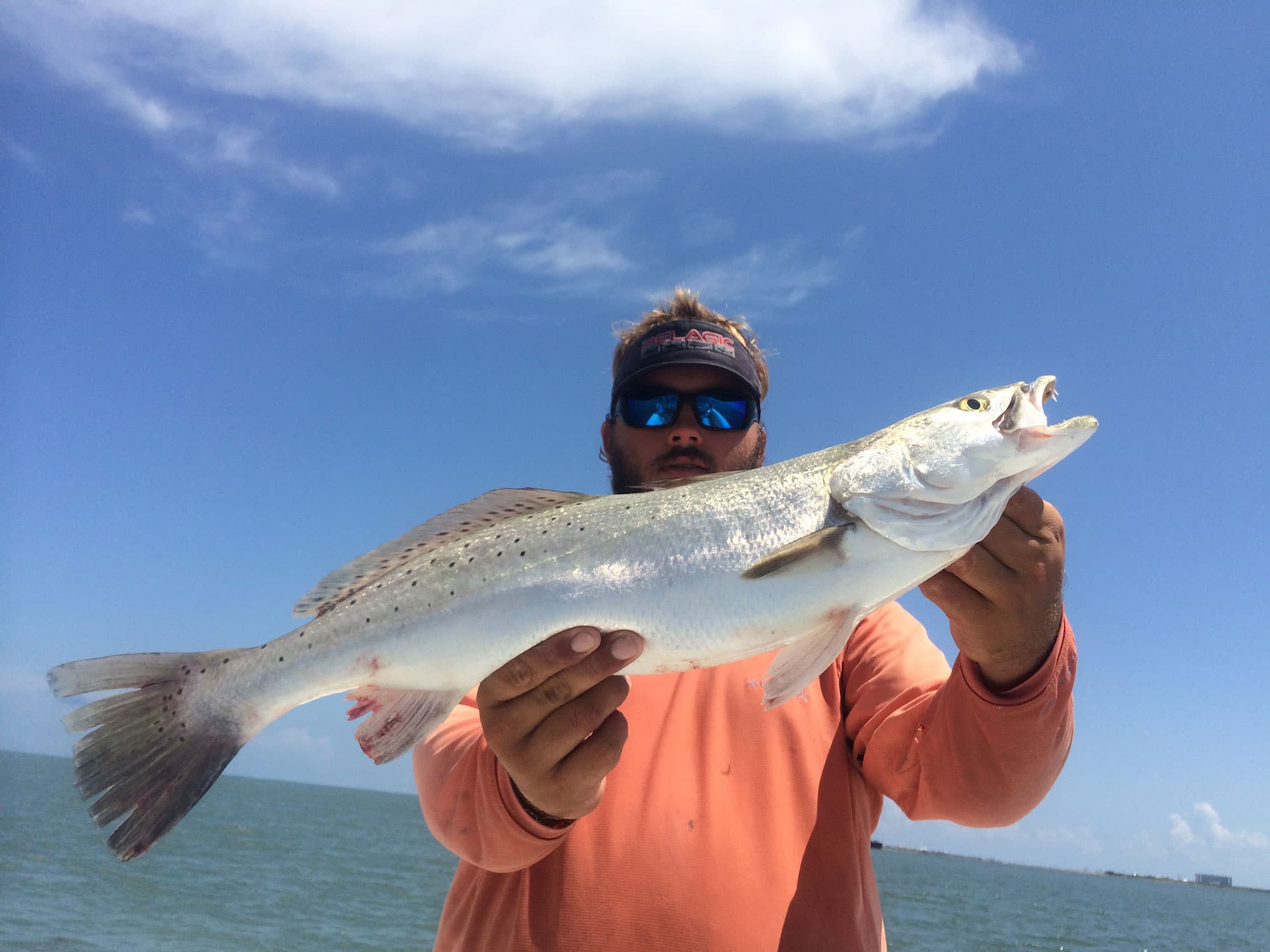 Man holding speckled trout caught on a Galveston fishing trip in Summer