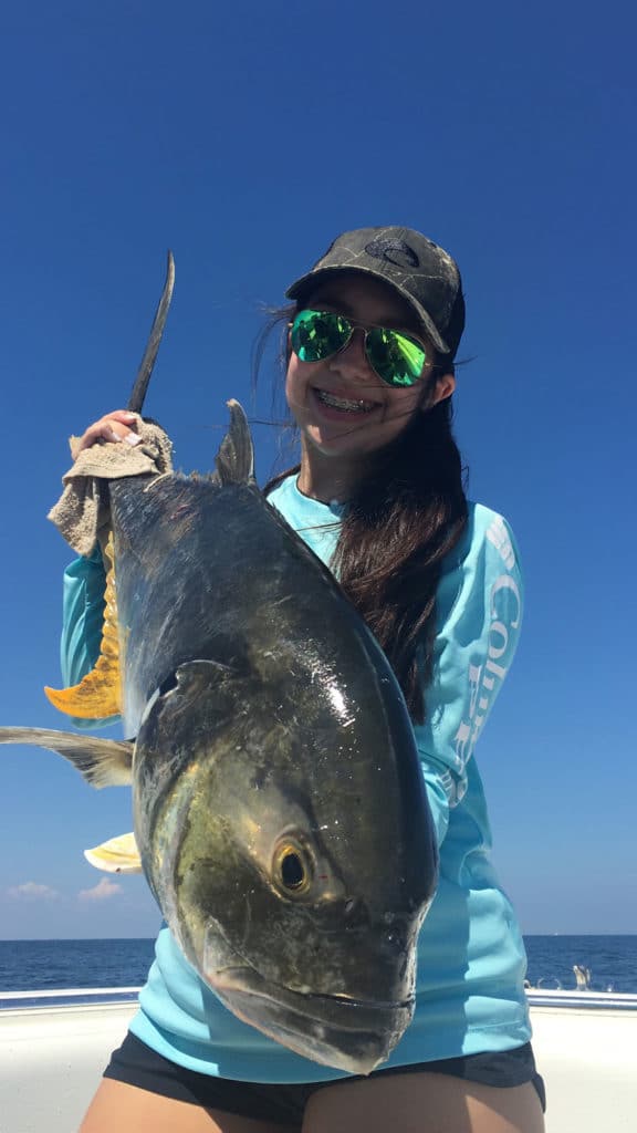 Young girl holds up a yellowfin tuna on a boat in beautiful Galveston Spring weather