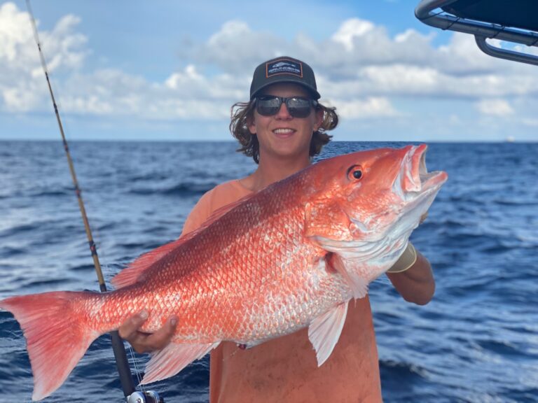 Male angler holding a large red snapper fish during red snapper season.