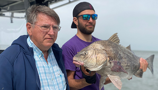 Father and son pose for a photo with a large fish caught on a nearshore Galveston fishing trip.