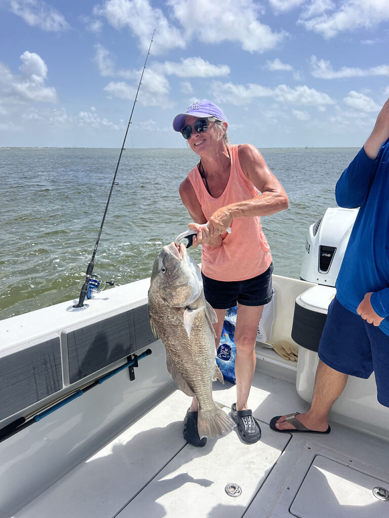 A woman holding a large, bull redfish that she caught on a Galveston  Redfish Fishing Charter.