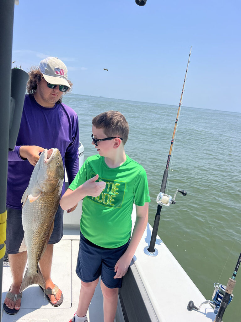 Two young brothers admire the redfish they caught in Galveston. 