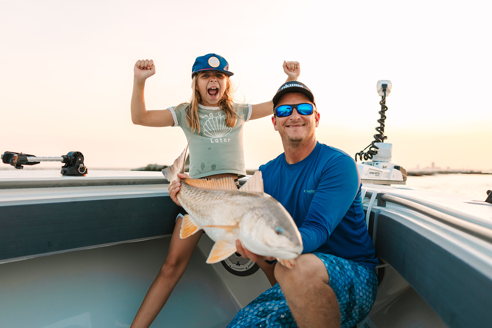 Young girl with her arms overhead, screaming with excitement about catching a large redfish on a Galveston Fishing Charter.