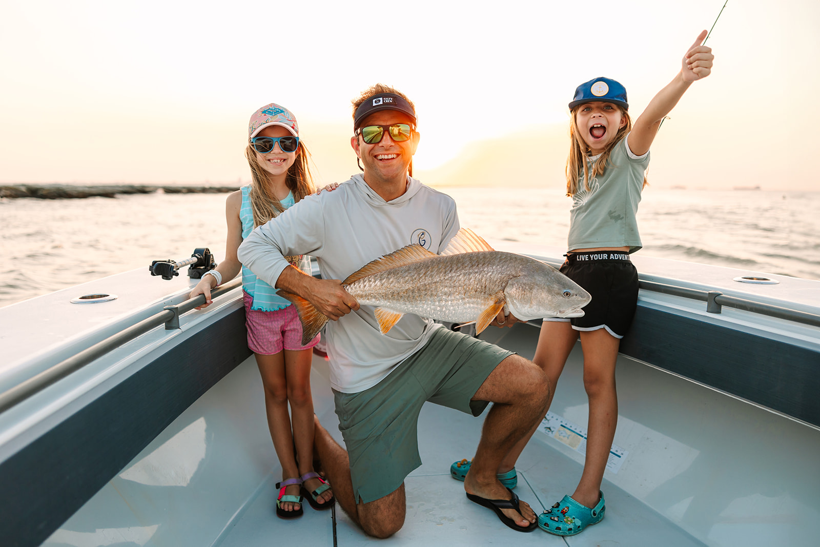 A father and his two daughters posing with the Redfish they caught on a Galveston Fishing Charter.