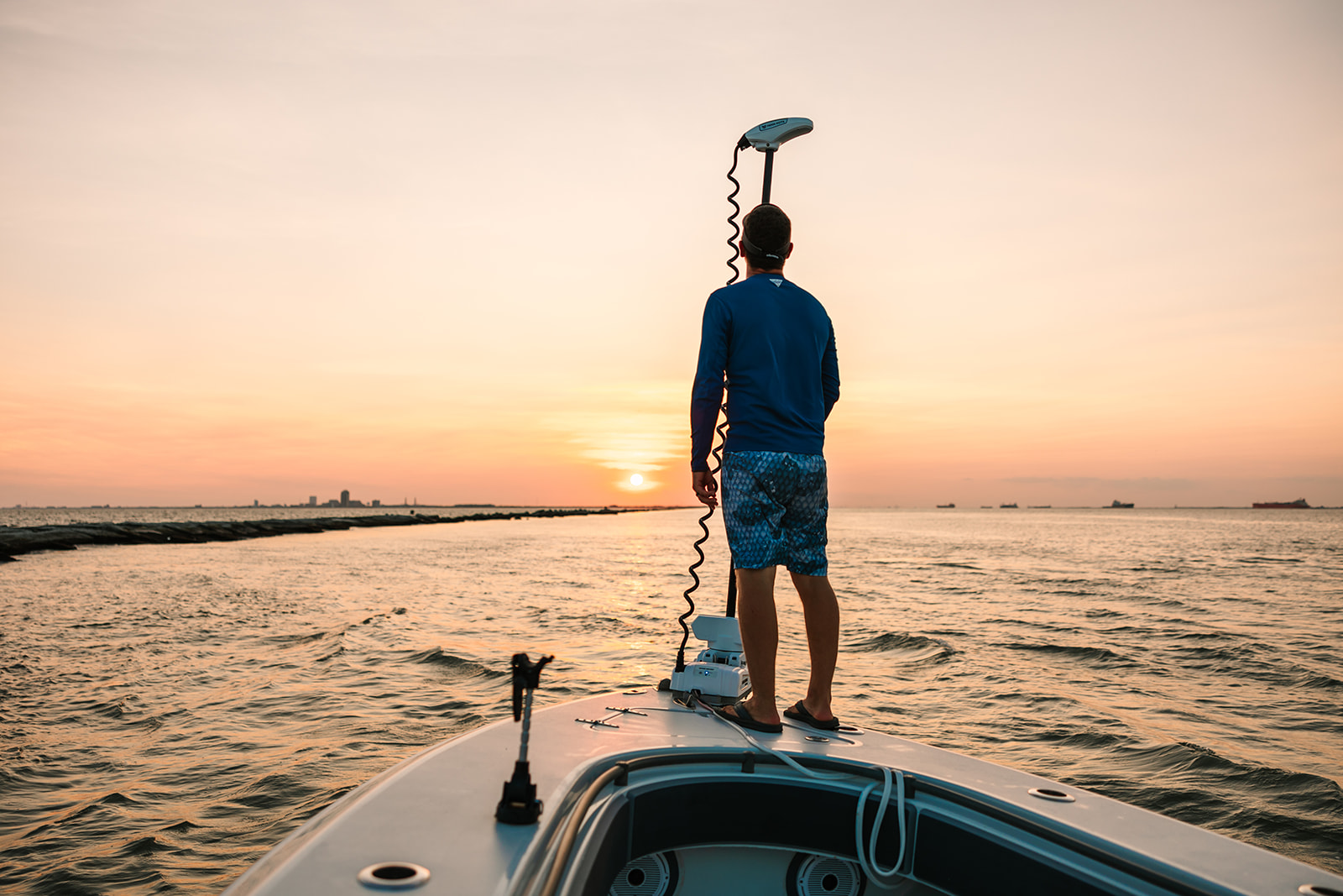 Captain Shane standing on the bow of his Galveston Fishing boat, watching the sunset.