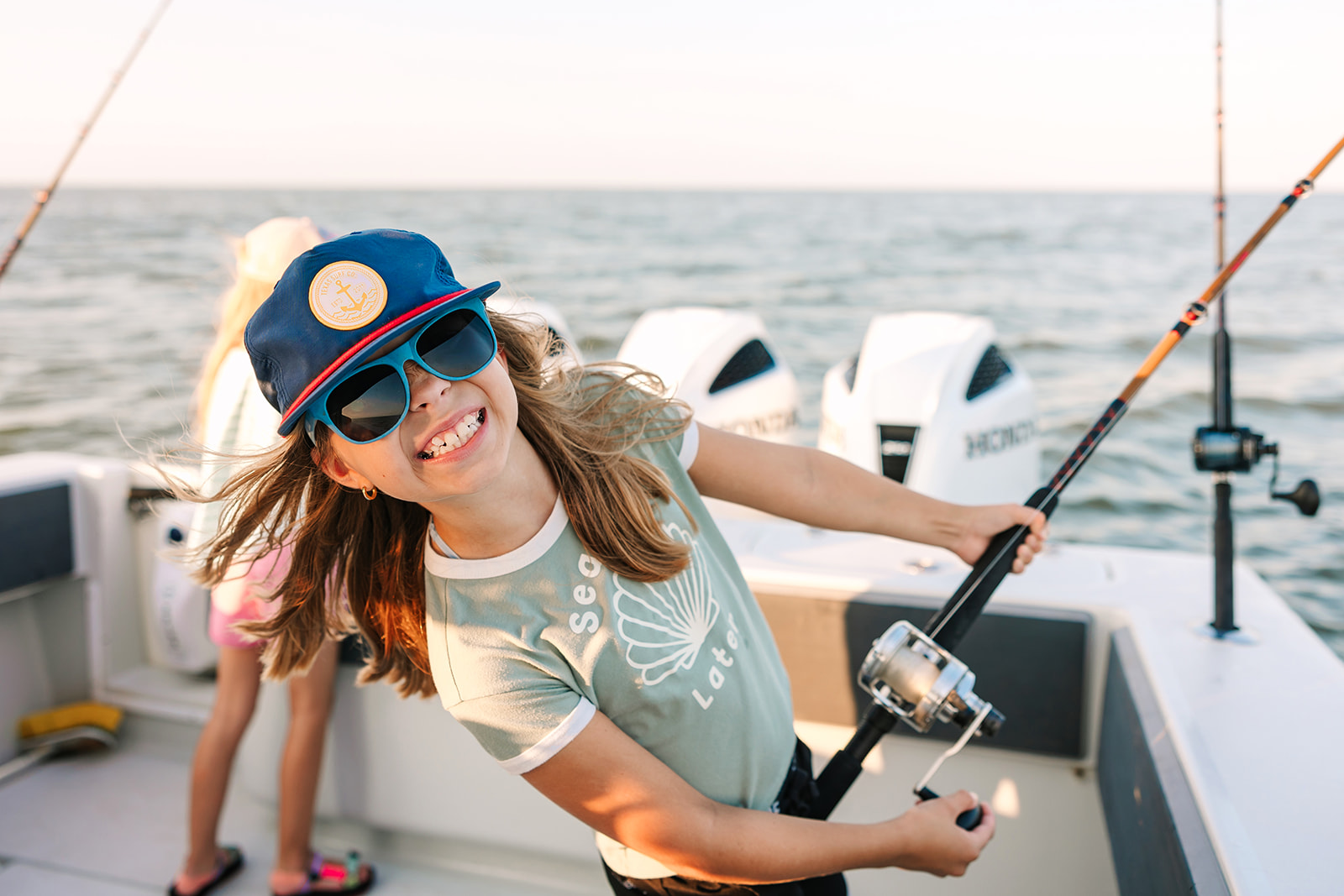 A young girl smiles as she reels in her fish on a Galveston Fishing Charter.