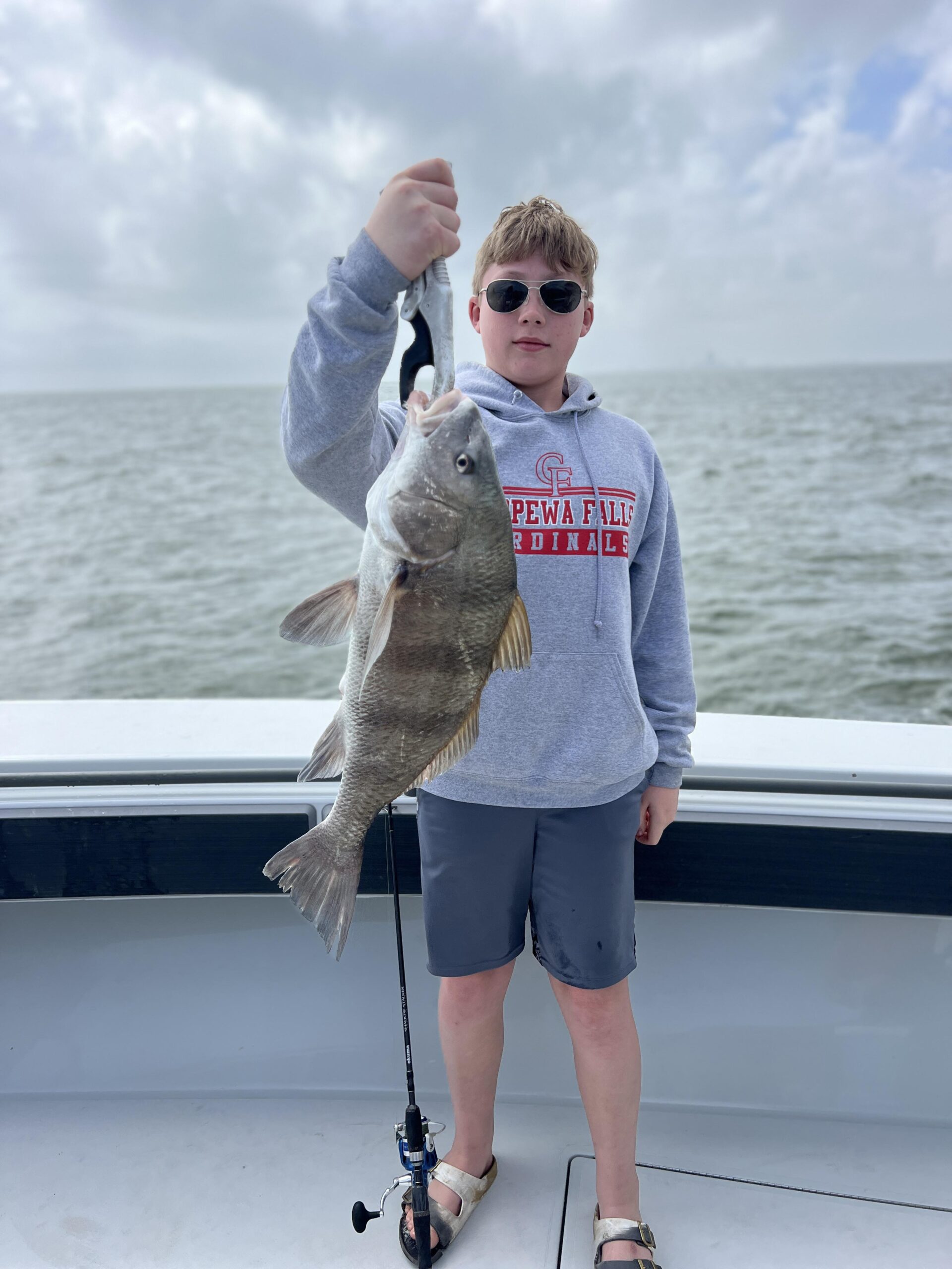 Teenage boy holds the drum fish he caught on a Galveston Bay & Jetty Fishing trip.