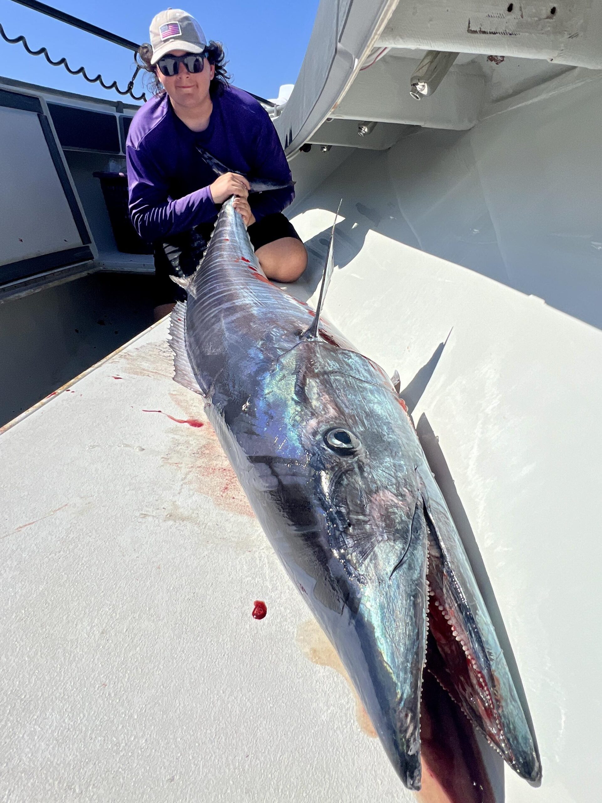 Man holds the large fish he caught on a deep sea fishing trip in Galveston.