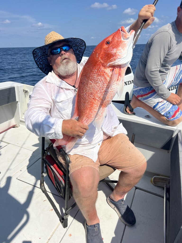 Man poses with a large red snapper caught on a Galveston fishing boat.