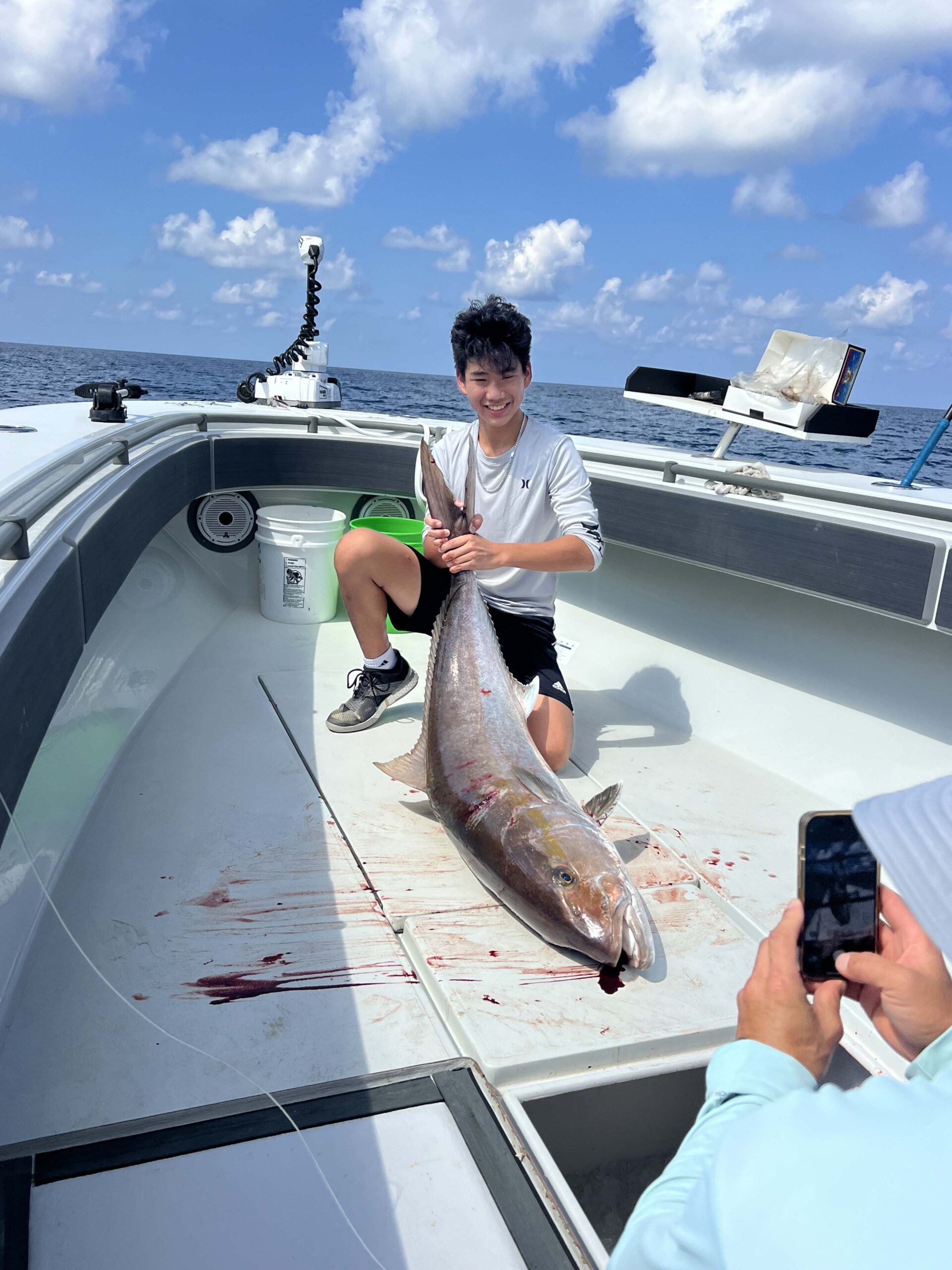 A young boy poses with his catch on the bow of a Galveston Fishing Boat.