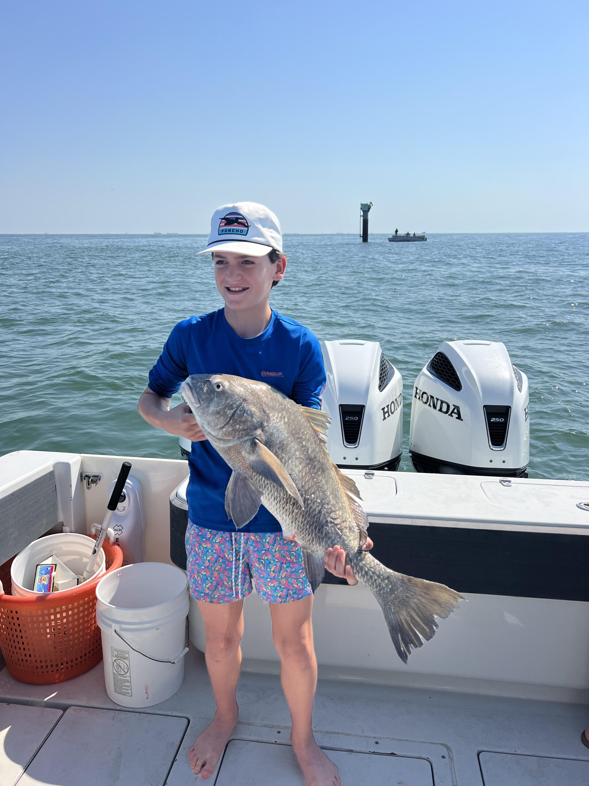 Young boy holds the fishing he caught on a Galveston Fishing Charter.