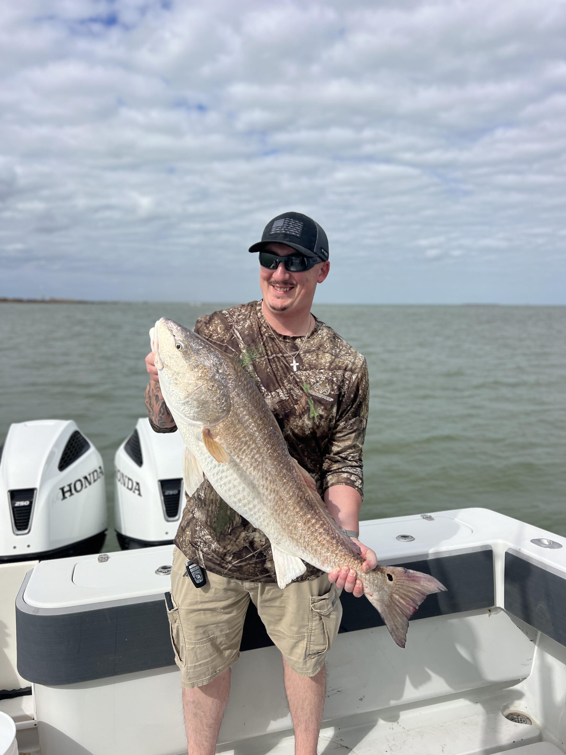 Fisherman poses with the large, bull redfish he caught on a Galveston Fishing Trip.